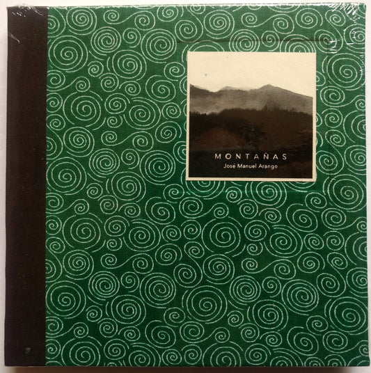Portada de «Montañas», de José Manuel Arango, en tela verde con espirales blancas y lomo marrón oscuro, envuelta en plástico